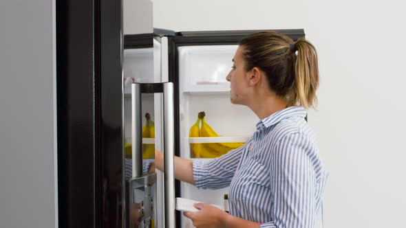 Woman Making List of Necessary Food at Home Fridge