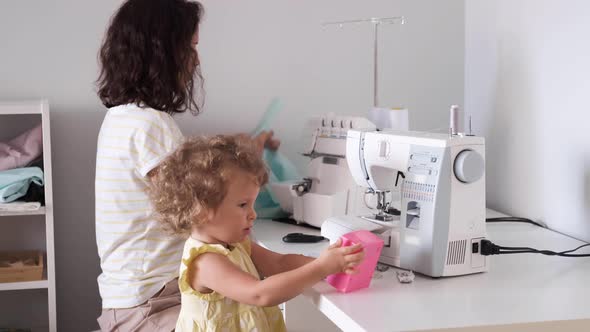 Mother Multitasking, Working at Home with Her Baby. Candide Genuine and Real Life Mom Works