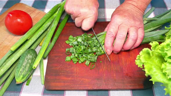 Slicing green onions with a knife on a cutting board
