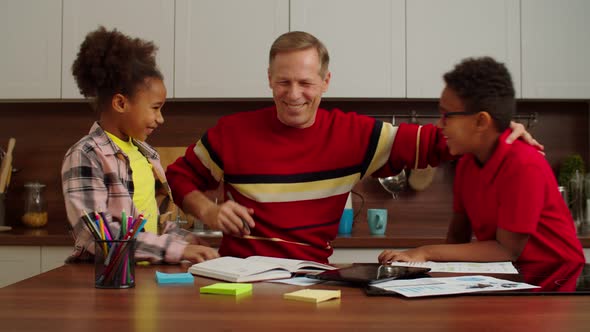 Loving Cute Multicultural Grandchildren Embracing Happy Grandpa Indoors