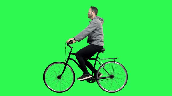 Happy Man Riding a Bicycle Over a Green Screen, Looking Around