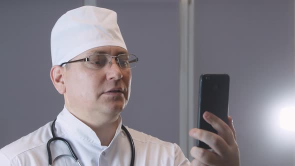 a doctor in uniform with a stethoscope talks to a patient in a video chat application, video confere