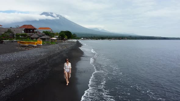 Woman Walks Along the Black Sand Beach