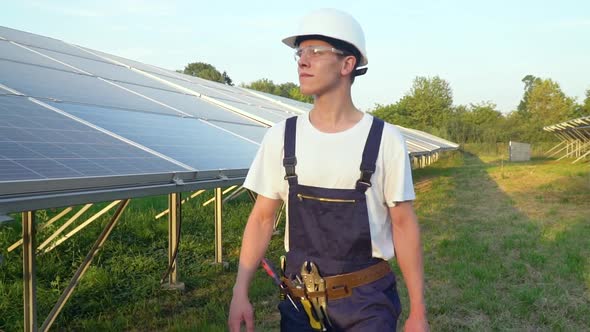 Technician Walking in Solar Cell Farm Through Field of Solar Panels Checking the Panels at Solar