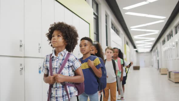 Video of happy diverse pupils standing in row and smiling before entering classroom