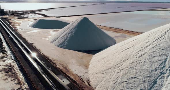 Drone Flying Above White Salt Mountains in Front of a Rose Lake with Salt Water