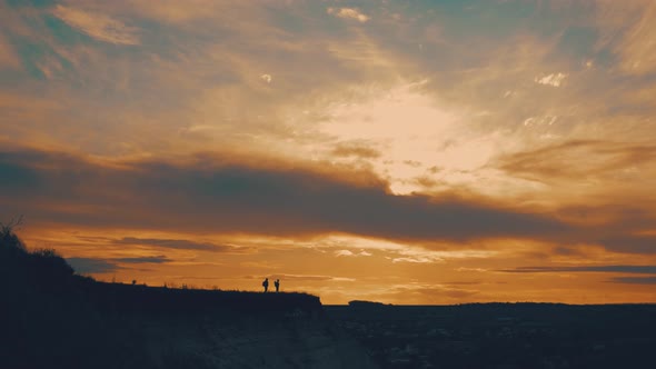 Silhouettes of Two Hikers with Backpacks Enjoying Sunset View From Top of a Mountain. Enjoying the