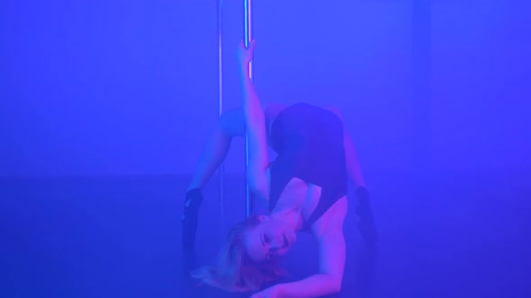 Young Sexy Slim Woman Pole Dancing with Pylon in Dark Interior