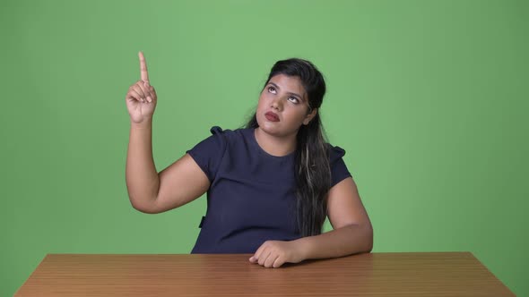 Young Overweight Beautiful Indian Businesswoman Against Green Background