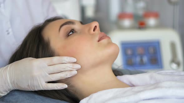 Young Woman Enjoying of Facial Massage in Beauty Salon