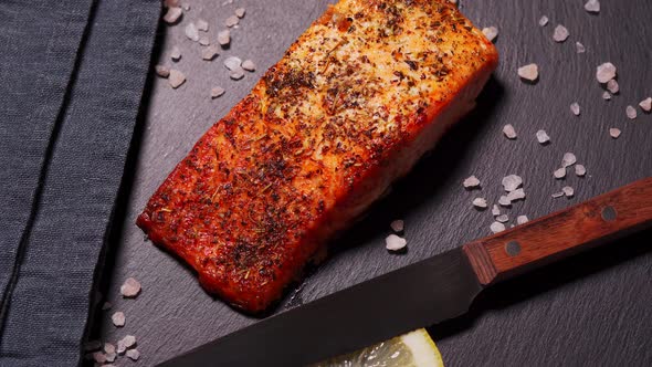 Delicious Baked Golden Salmon on a Black Plate in the Kitchen