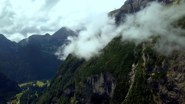 Cloudy Dolomite mountains with green foliage in northern Italy with meadow below on a winter day, Ae