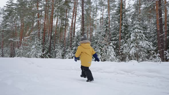 A Little Boy of 34 Years Old Runs in the Winter Forest a View From the Back in Slow Motion in a