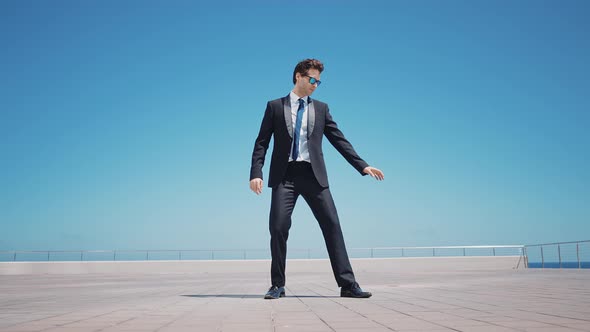 Flexible and cool businessman doing acrobatic tricks outdoor