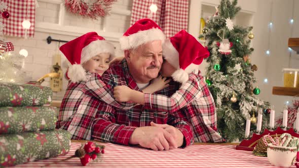 Children Are Hugging Their Grandfather at Christmas Table