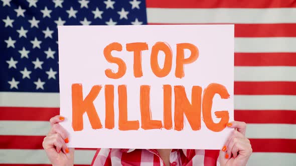 Protester Holds a Banner with a Slogan - Stop Killing - Against Background of the USA Flag. Fighting