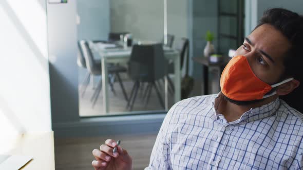 Middle eastern man wearing face mask taking note at modern office