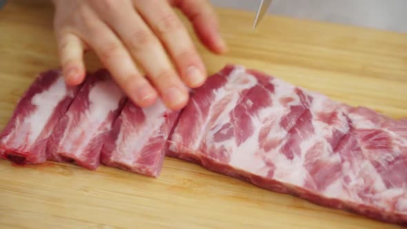 Crop housewife cutting raw ribs