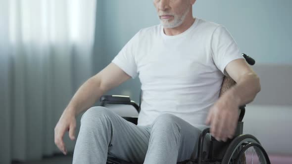 Helpless Man with Disabilities Sitting in Wheelchair, Turning Back to Camera