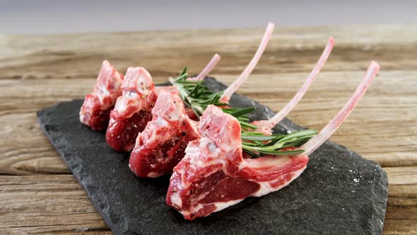 Raw meat chops and rosemary arranged on the stone tray