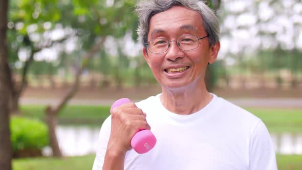 Asian senior man exercising in a green park.