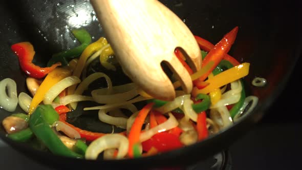 Wooden fork mixing vegetables in wok