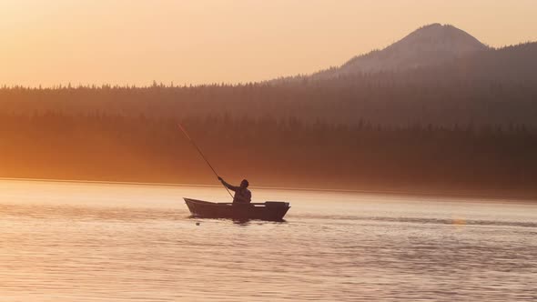 A Silhouette of Man Sitting in a Boat - Fishing on Nature While the Sunset