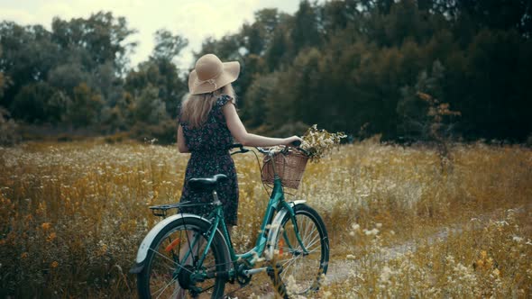 Girl In Sunglasses And Dress. Woman In Hat Enjoying Weekend. Woman Cyclist Walking With Bike.