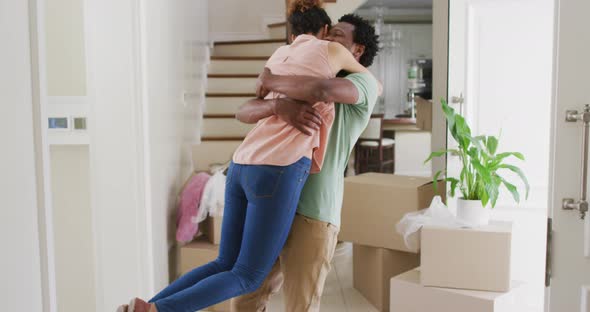 Happy biracial couple hugging with joy in new house