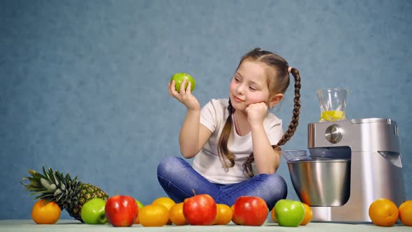 Pretty little girl sitting on the desk and eating apple. 