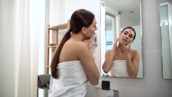 Skin Care. Woman Touching Face And Looking At Mirror At Bathroom