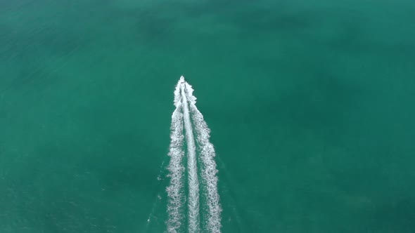 4k drone chasing boat in blue water sunny day