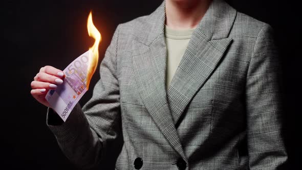 Woman Holding Burning Five Hundred Euro Banknote on Black Background