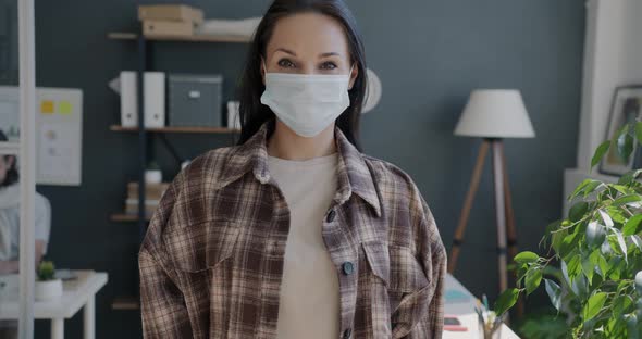 Slow Motion Portrait of Female Office Worker Wearing Face Mask Looking at Camera in Workplace