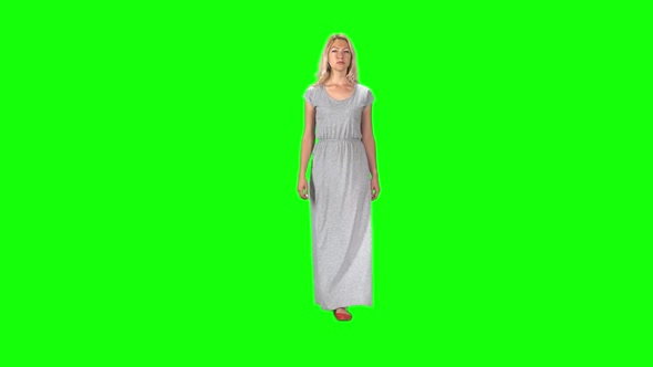 Blonde Girl in a Long Grey Dress Going and Looking Straight Into the Camera Against a Green Screen