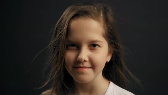 Portrait of Little Young Girl Looking at the Camera. Black Background in the Studio. Slow Motion