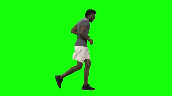 African American Man Is Running at Green Screen, Chroma Key. Profile View. Slow Motion