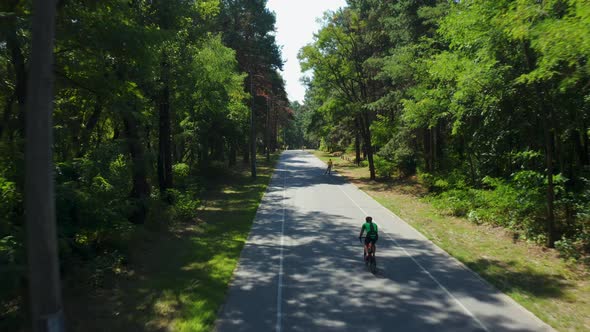 Aerial Tracking Shot of Cyclist Riding Bike on Forest Road