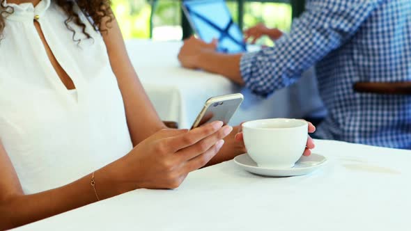 Woman using mobile phone while having coffee