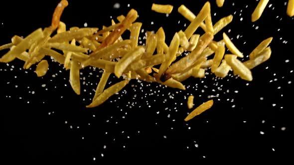 Slow Motion of Flying Fresh French Fries on Black Background.