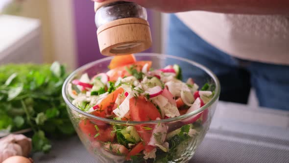 Woman Adding Salt and Spices Into Mixed Salad of Vegetables  Tomatoes Cucumbers Onion Parsley