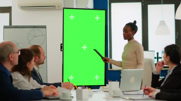 Diverse Woman Standing in Start Up Office Discussing Strategy with Green Screen Display