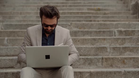 Tired Worker Overworked On Laptop. Frustrated Businessman Sitting On Steps. Remote Work Overtime.