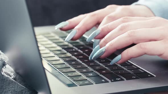 Secretary hands with long nails typing on modern keyword laptop device, close up slow motion of cauc