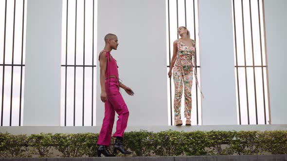 Man in Pink Clubwear Walking Passed Young Woman Posing