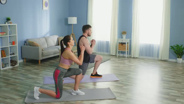 Active Couple Is Doing Forward Lunges at Home