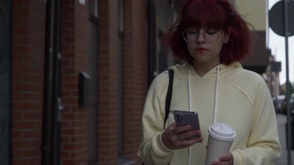 Young redhead Ukrainian teen girl with mobile phone on city street