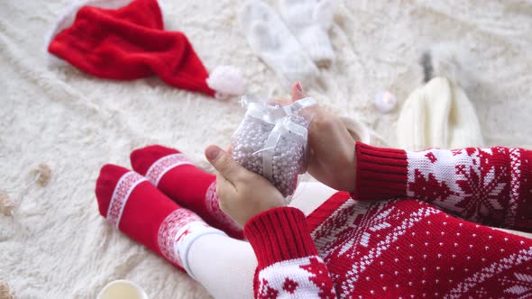 Woman Sitting on a Fluffy Blanket and Holding Present Box. Christmas and New Year Celebration