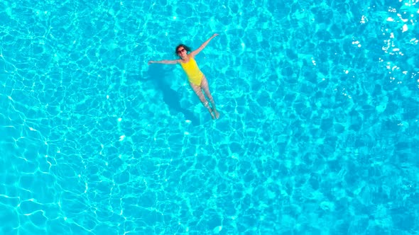 View From the Top As a Woman in a Yellow Swimsuit Lying on Her Back in the Pool