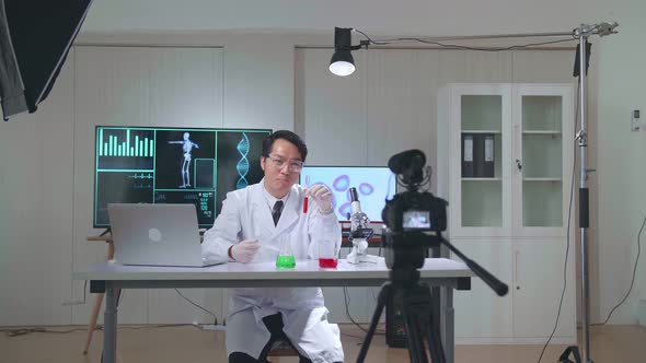 Male Scientist Holding Glass Test Tube And Speaking To The Camera With Professional Lighting alt